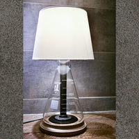 Modern industrial table lamp with rustic bronze and copper hardware, glass, wood base, and beige lamp shade